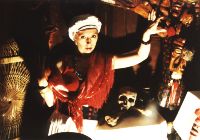 Voodoo Priestess Severina standing before an Altar with a skull resting on it